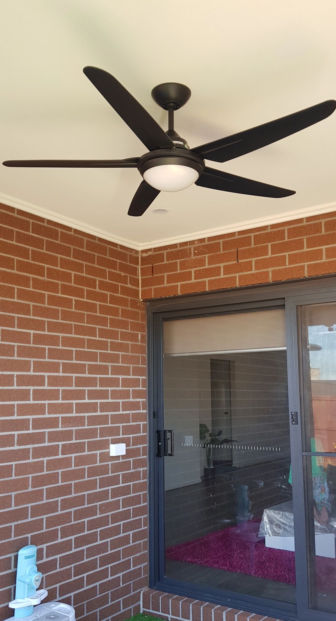 Dark bronze outdoor ceiling fan on covered patio