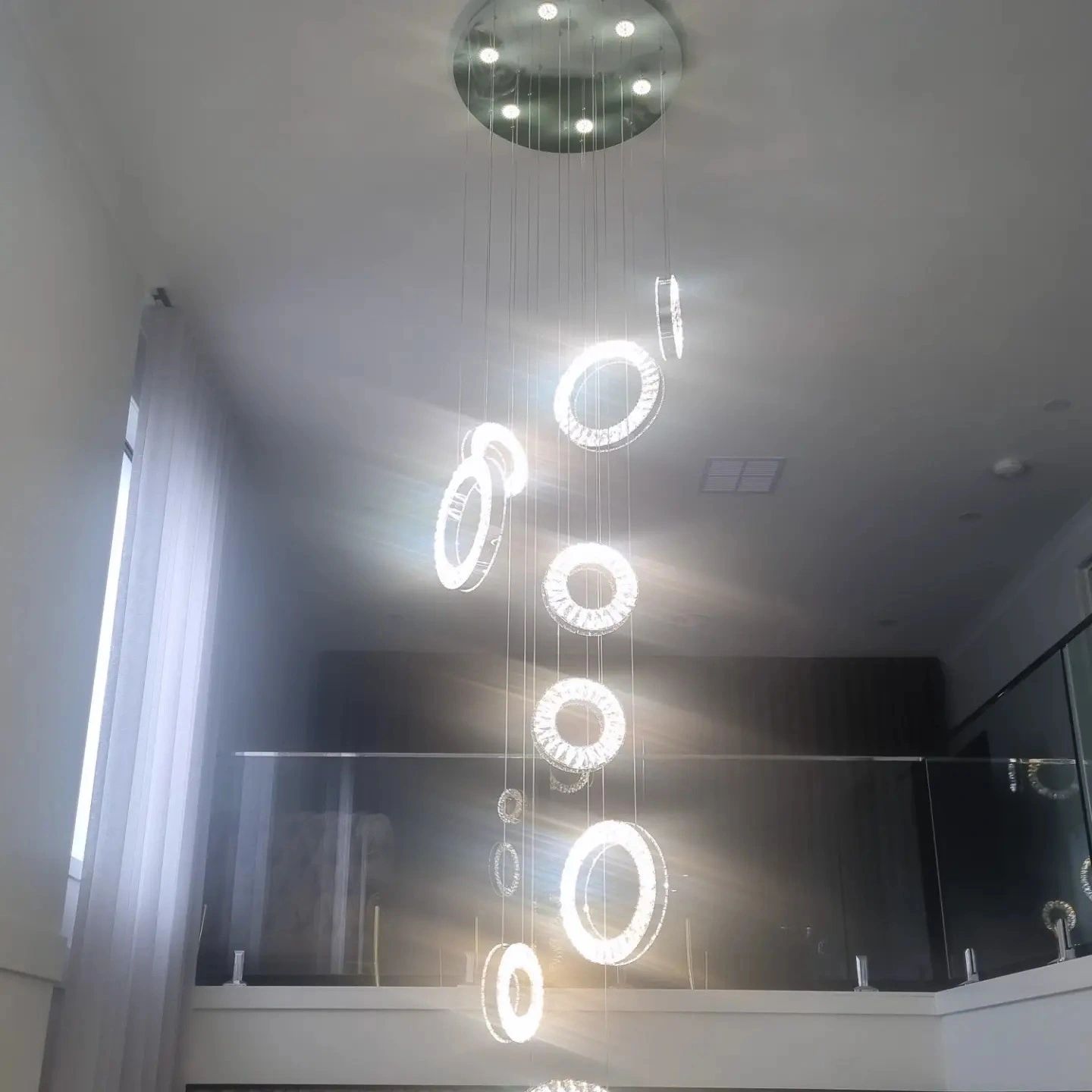 Crystal ring chandelier lit stairwell full length